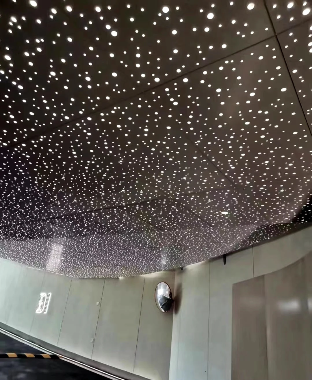 Dark curved perforated ceiling with points of light